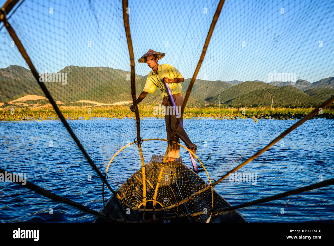 Asian pescatore con rete da pesca in canoa sul fiume Foto Stock