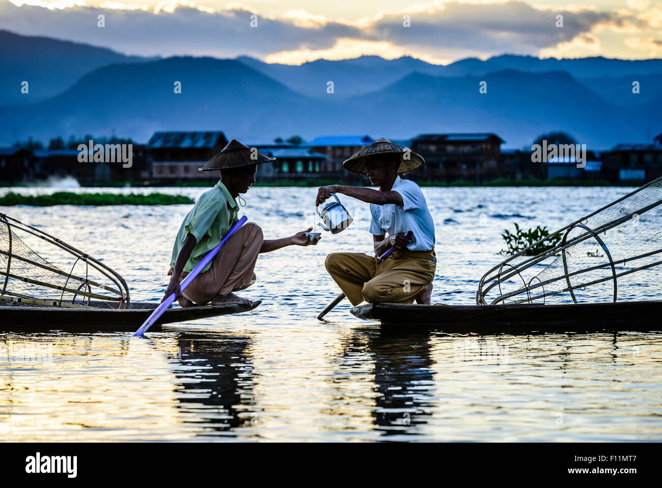 I pescatori asiatici la condivisione di tè in canoa sul fiume Foto Stock