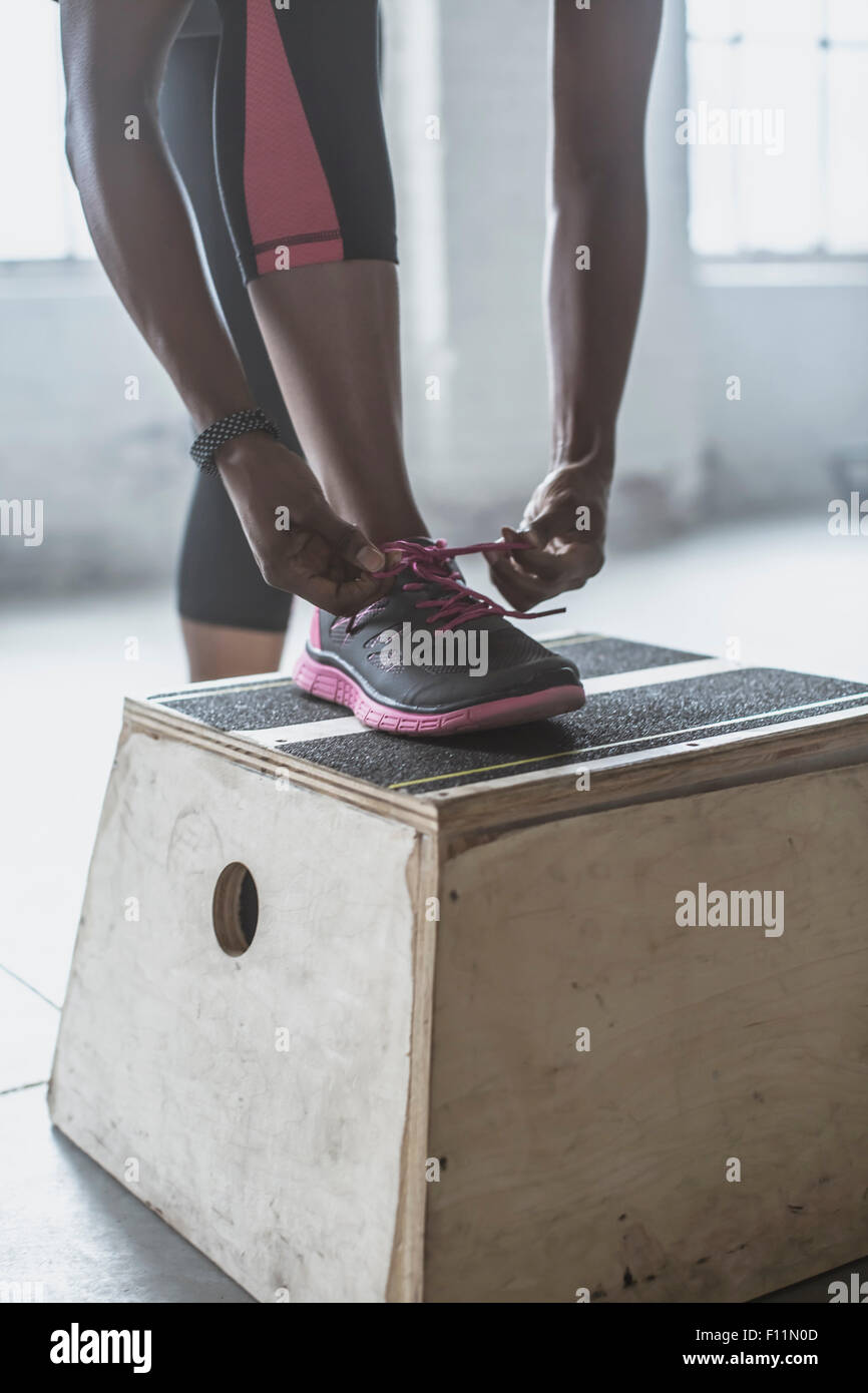 Atleta legando le sue scarpe su piattaforma in palestra Foto Stock