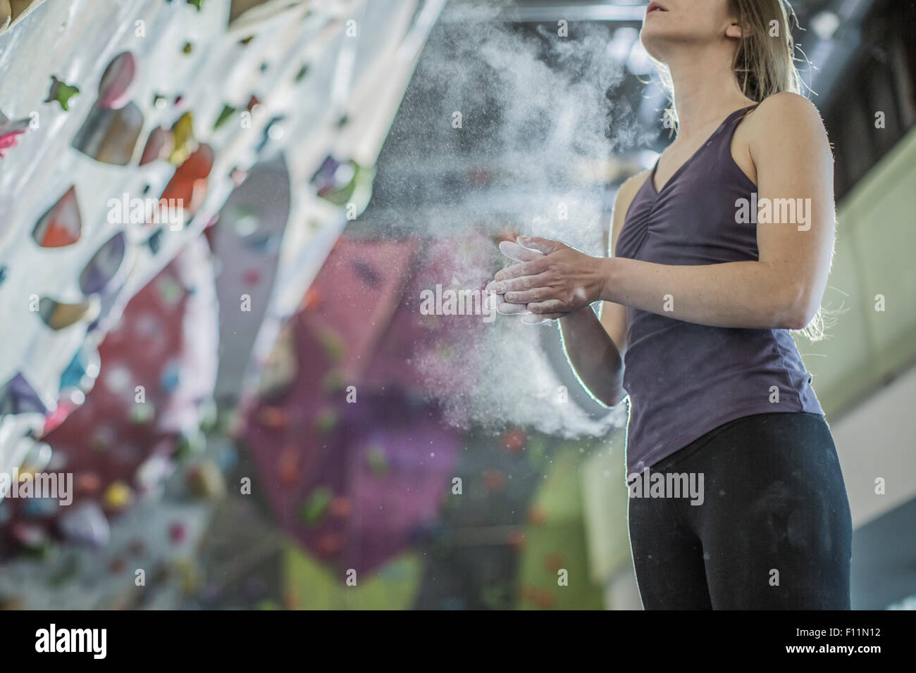 Atleta lo sfarinamento le mani alla parete di roccia in palestra Foto Stock