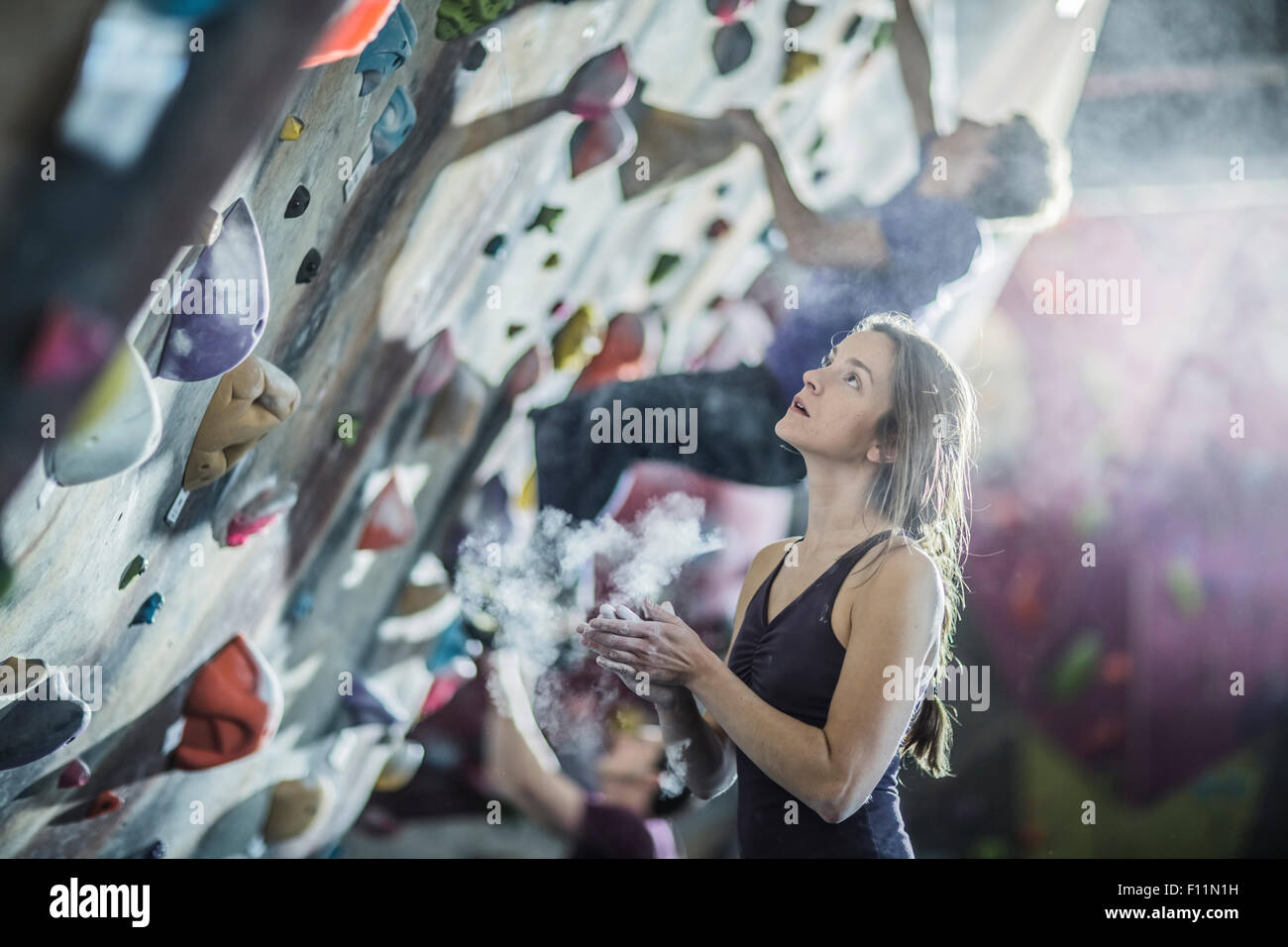 Atleta lo sfarinamento le mani alla parete di roccia in palestra Foto Stock