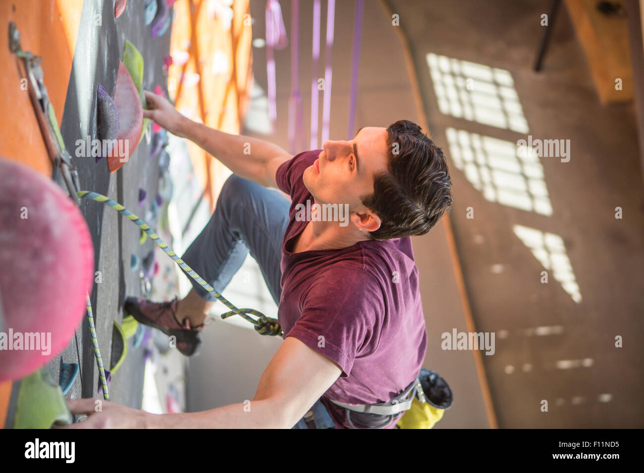 Angolo di alta vista di atleta arrampicata su parete di roccia in palestra Foto Stock