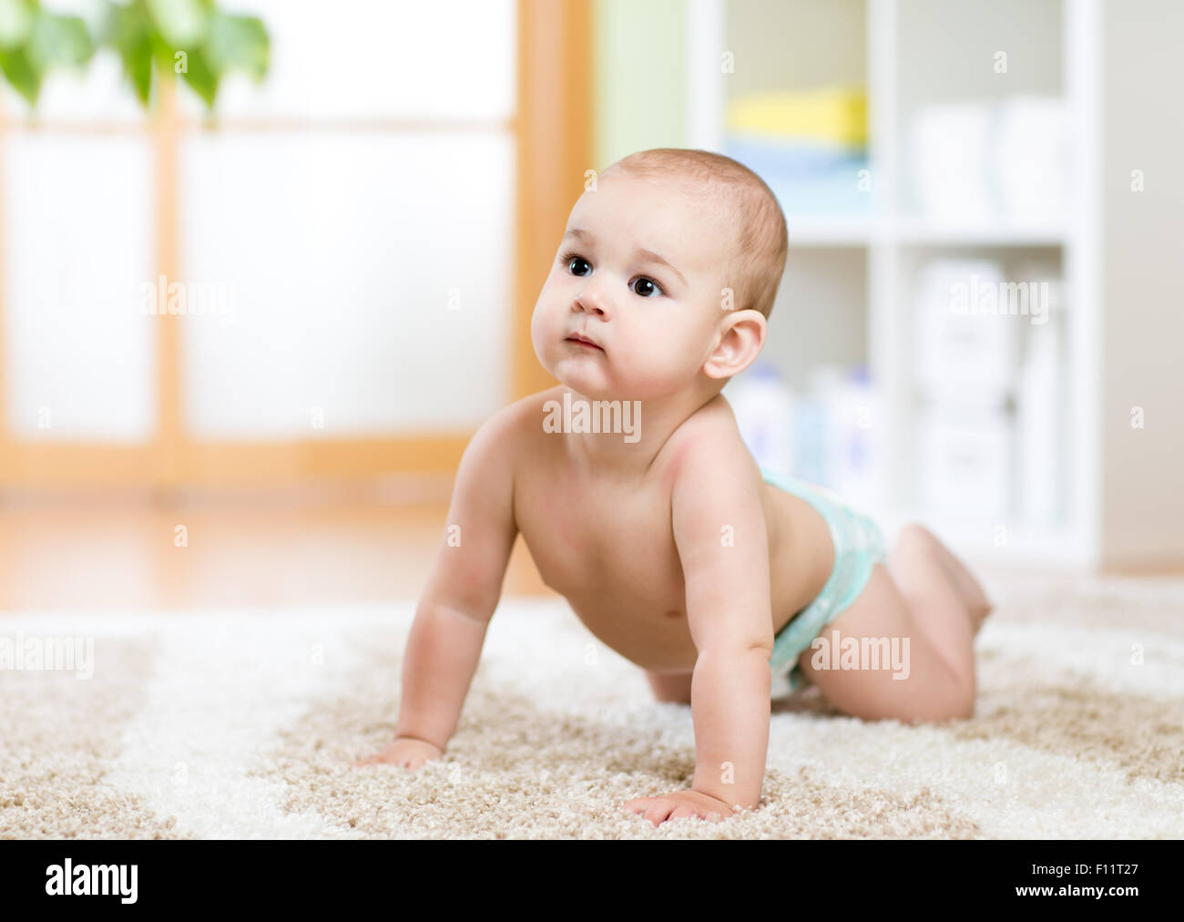 Baby usurata nel pannolino strisciare sul pavimento Foto Stock