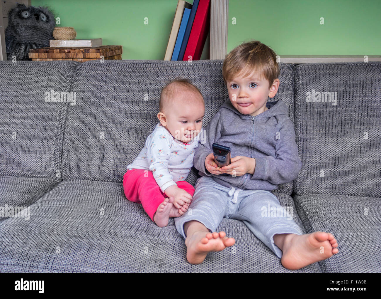 Due bambini piccoli di guardare la televisione sul lettino Foto Stock