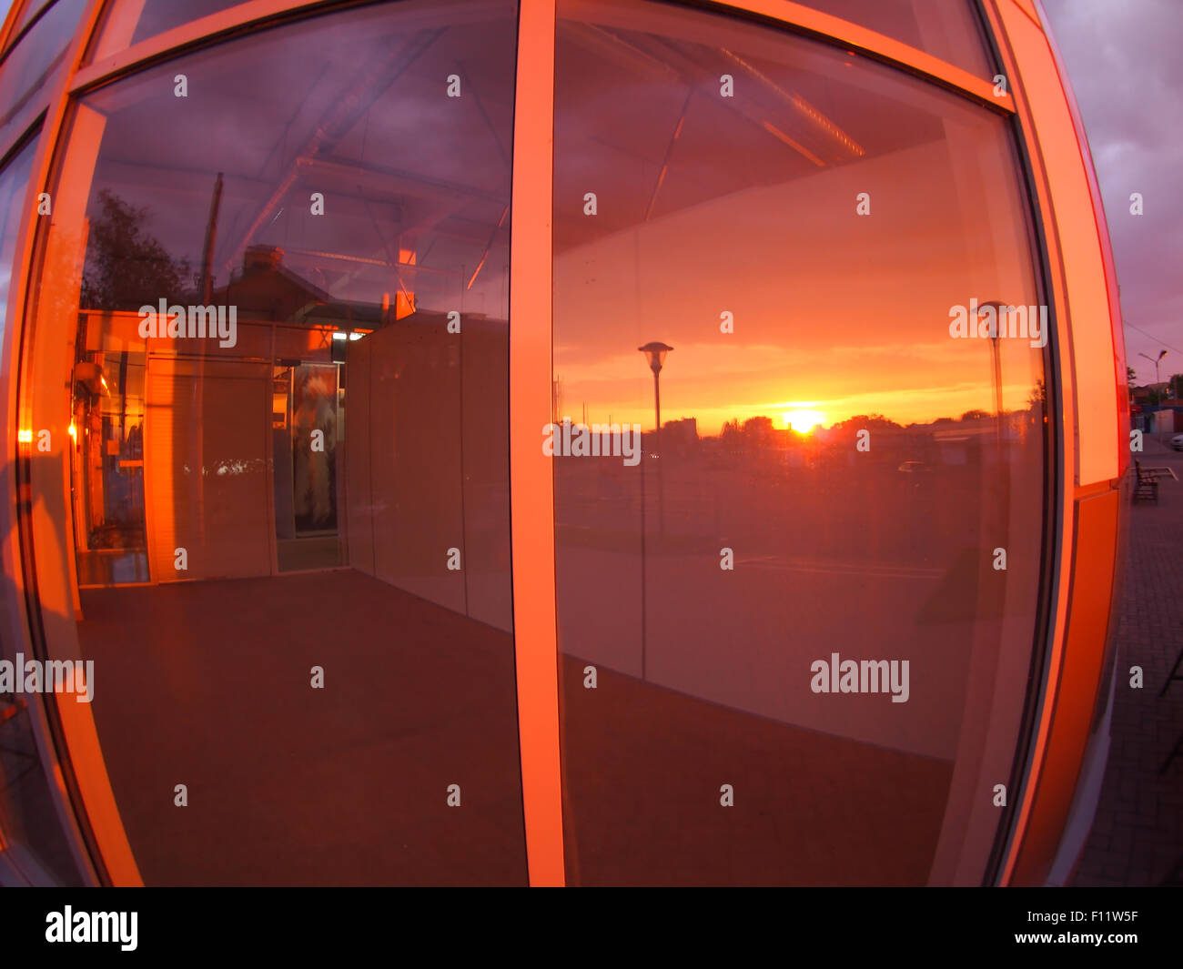 Paesaggio al tramonto, che è riflessa nella vetrina di un negozio vuoto locali con ampio angolo lente fisheye e vista di distorsione Foto Stock