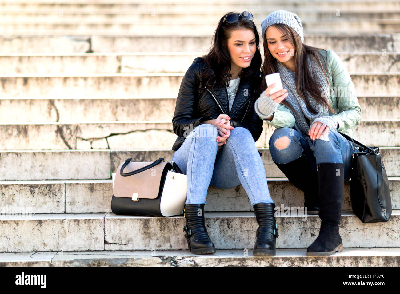 Due giovani e belle donne seduti a scale e prendendo un selfie Foto Stock