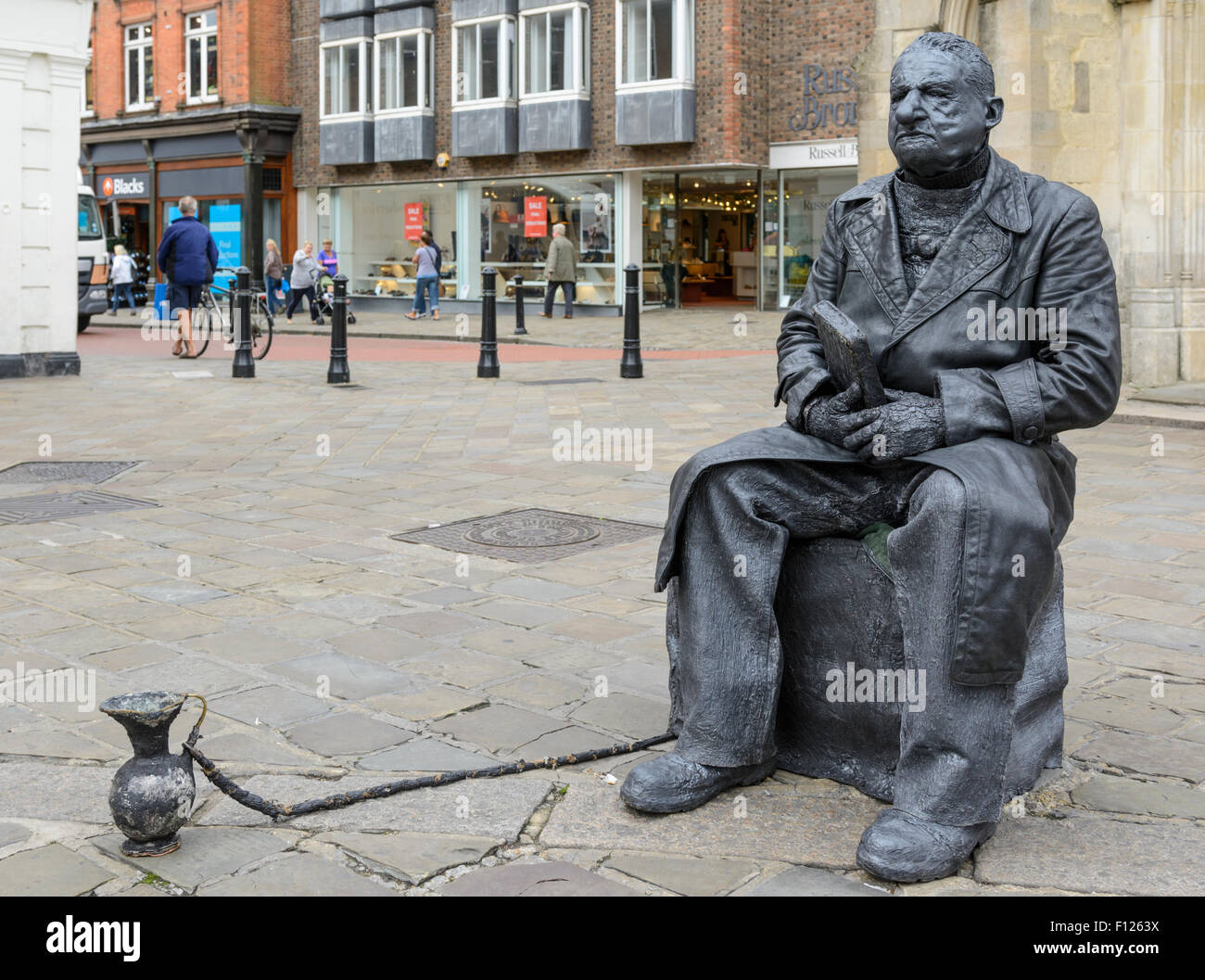 Statua vivente street performer con un vaso di raccolta in un centro commerciale a Chichester, West Sussex, in Inghilterra, Regno Unito. Foto Stock