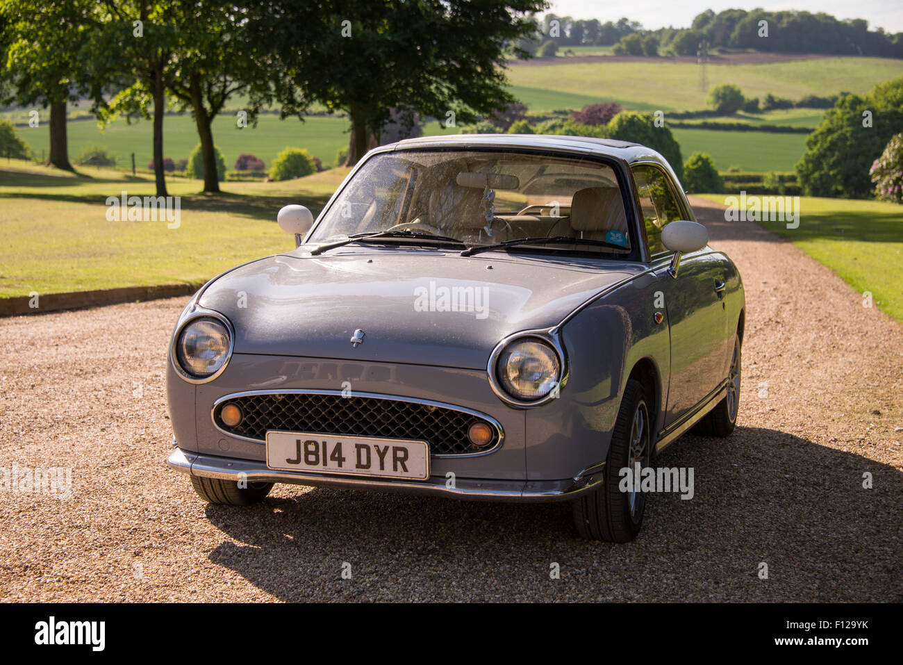 Nissan Figaro vintage automobile parcheggiata nel giardino di una dimora signorile, Inghilterra, Regno Unito. Foto Stock