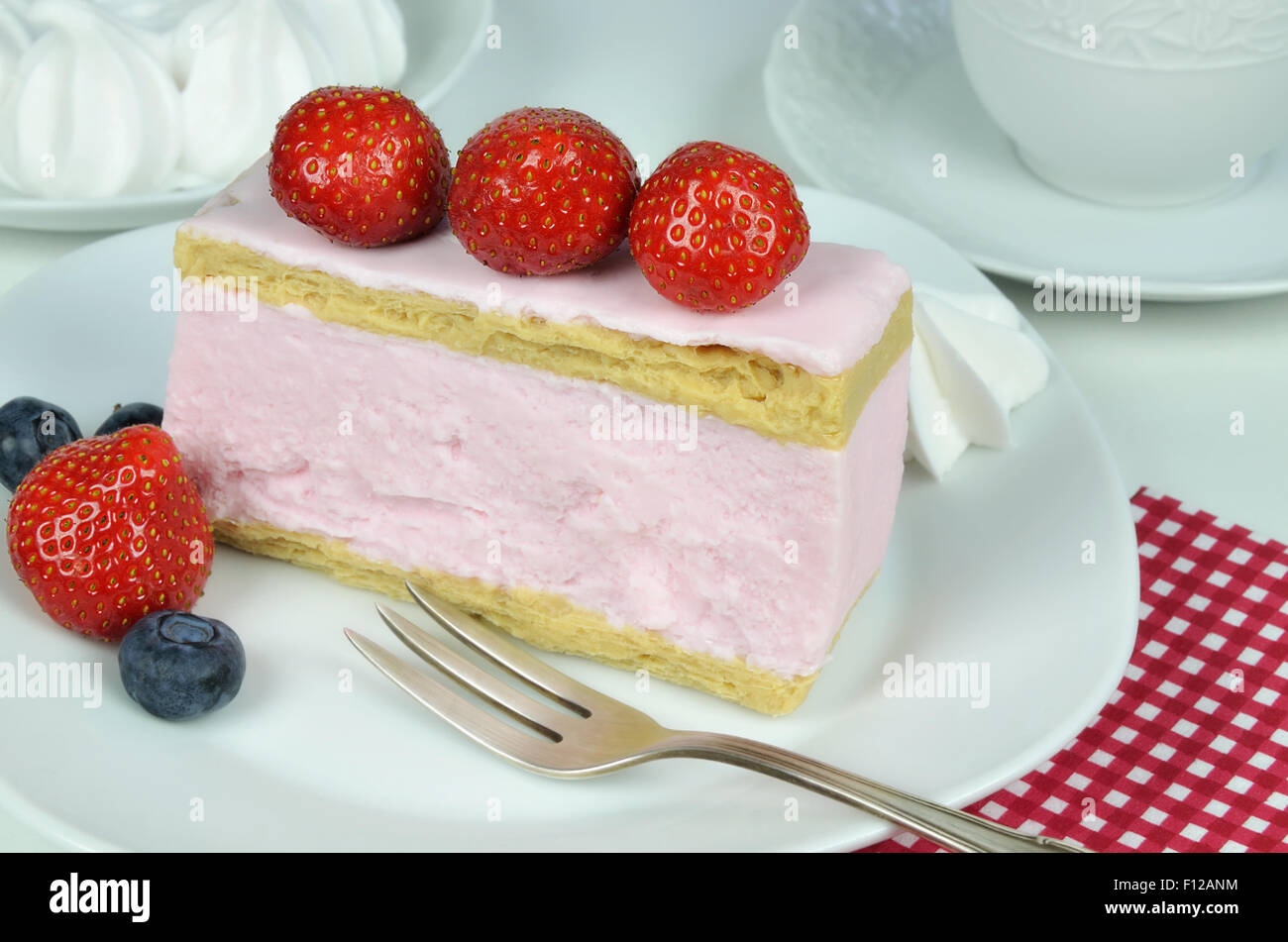 Close up di un pezzo di fragola fancy la torta con panna montata e pasticceria forcella sulla piastra bianca, macro, dettaglio, orizzontale Foto Stock