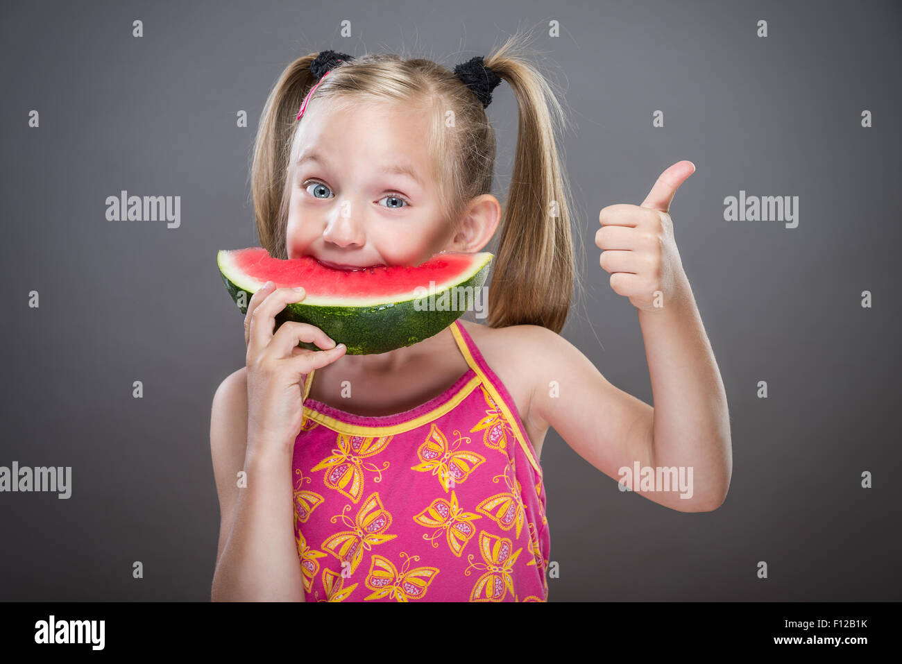 Piccola ragazza priva di denti mangiando anguria. Foto Stock