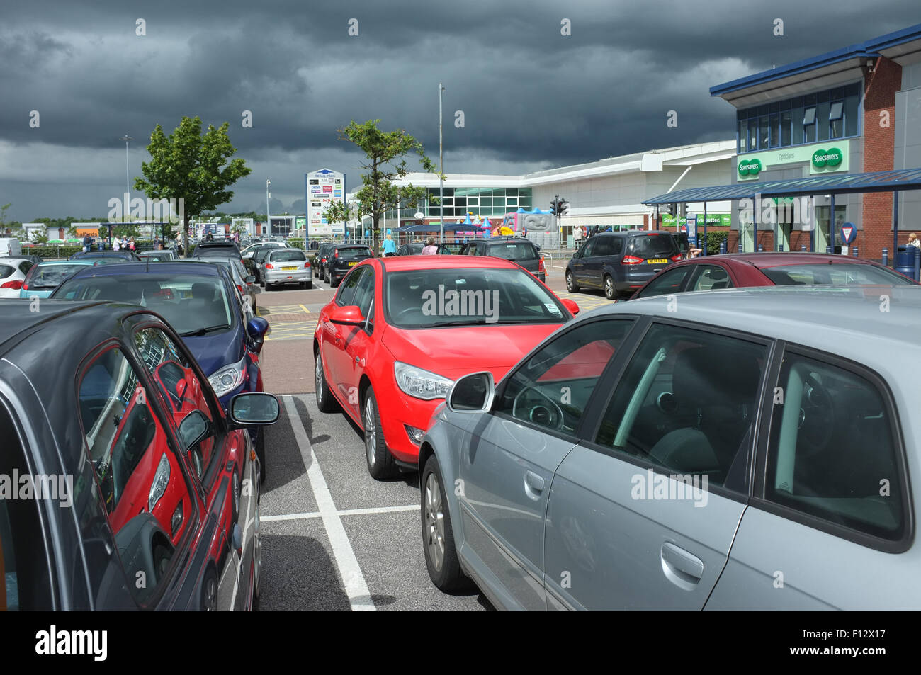 Nuvole scure raccogliendo oltre le macchine parcheggiate al Middlebrook Retail Park Horwich vicino a Bolton LANCASHIRE REGNO UNITO. fotografia DON TONGE Foto Stock
