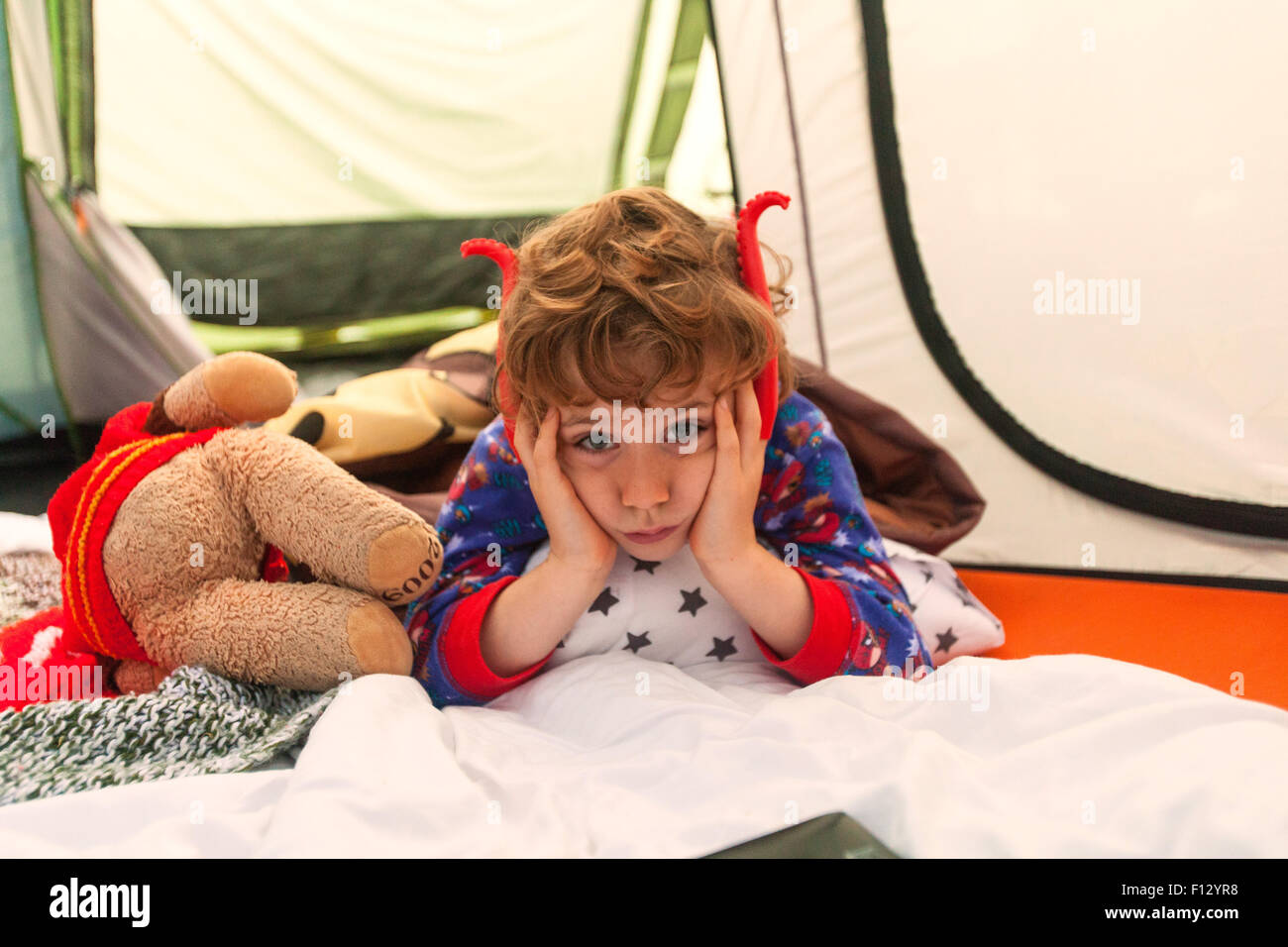 6 anno vecchio ragazzo cerca annoiato mentre camping. Campeggio Karrageen, Speranza Cove, Devon, Inghilterra, Regno Unito. Foto Stock