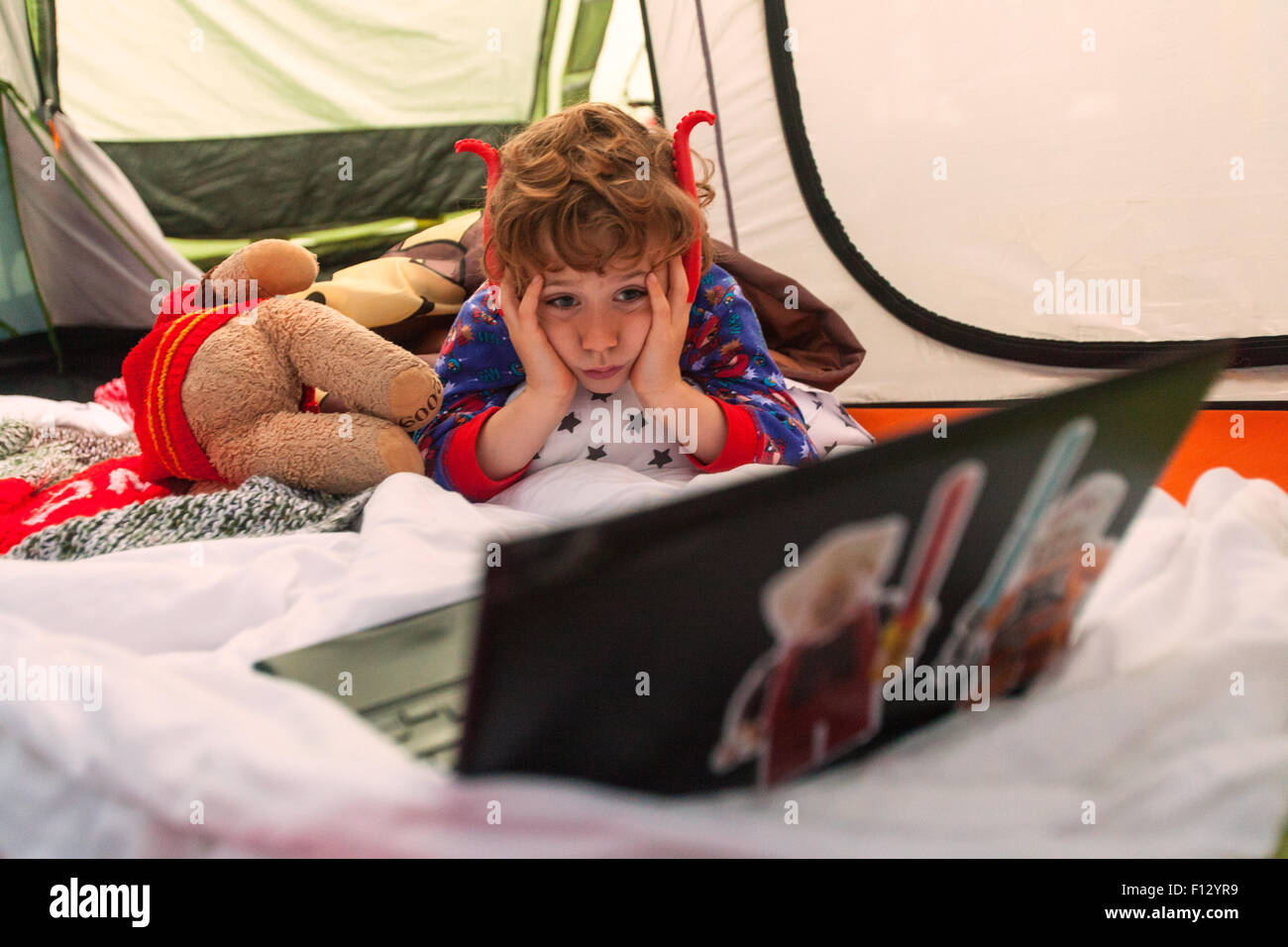 Sei anni di old boy in una tenda che guardano un notebook, Karageen Campeggio, Speranza Cove, Devon, Inghilterra, Regno Unito. Foto Stock