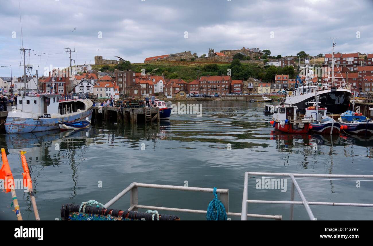 Barche da pesca in seduta Whitby Harbour con una chiesa e case in background. Foto Stock