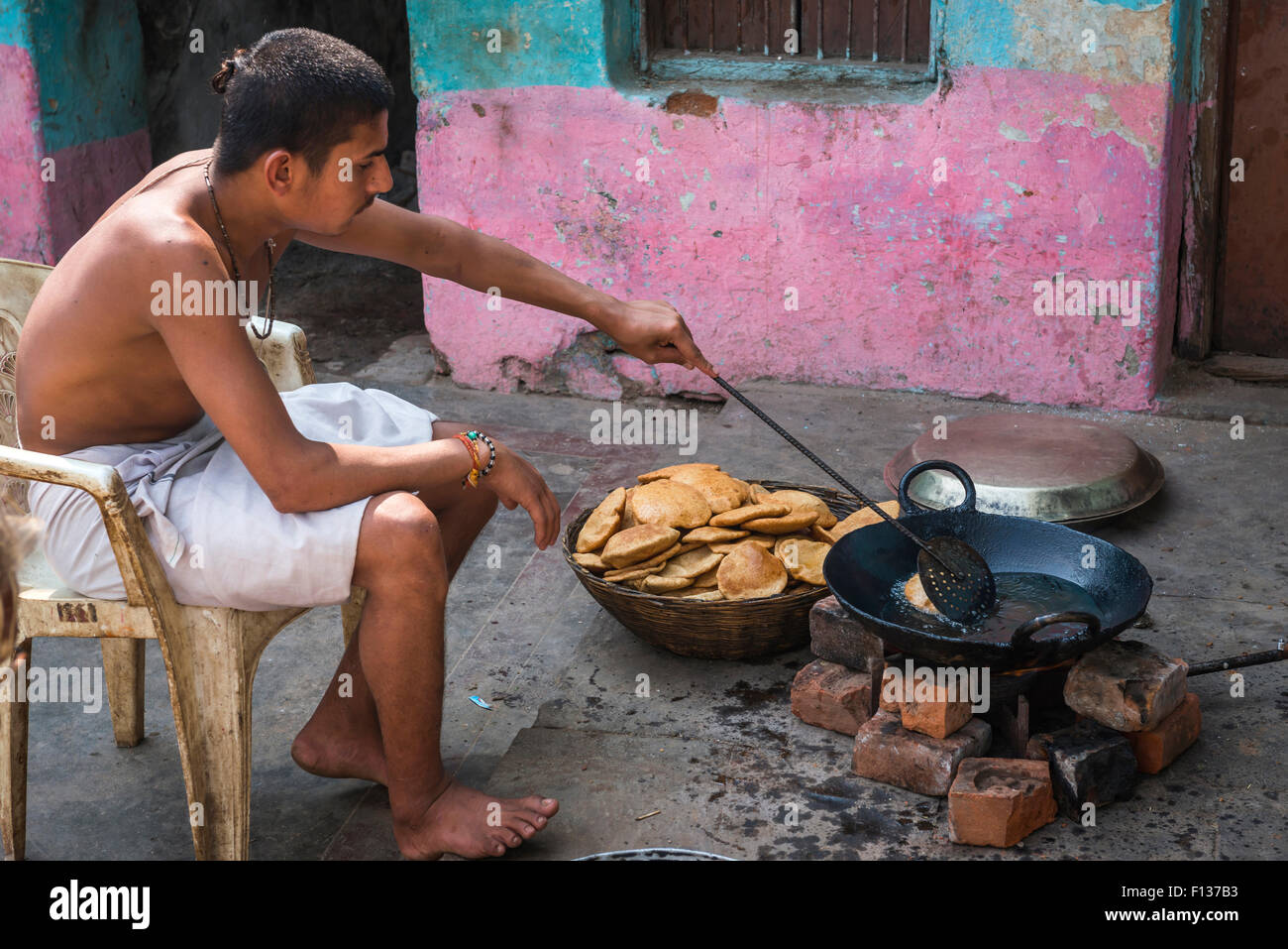 Un giovane uomo indù puris prepara in una padella in un ashram in Chitrakoot, (Chitrakut), Madhya Pradesh, India Foto Stock