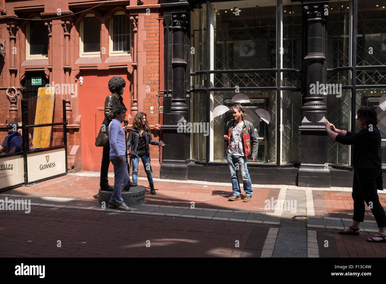 I turisti che posano per una foto con la dimensione di vita statua in bronzo di Phil Lynnot su Harry Street a Dublino centro città di Dublino in Irlanda Foto Stock