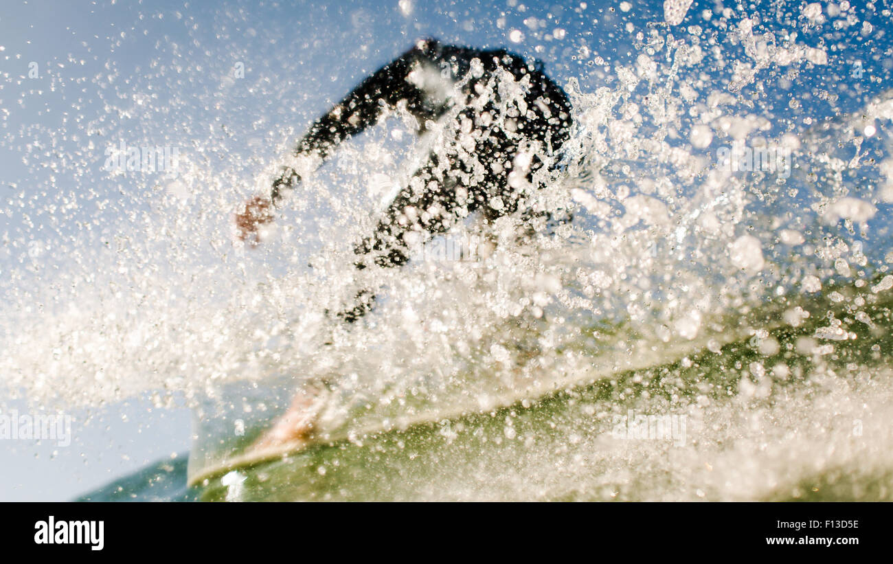 Basso angolo di visione di un surfista che vengono spruzzati da un'onda Foto Stock