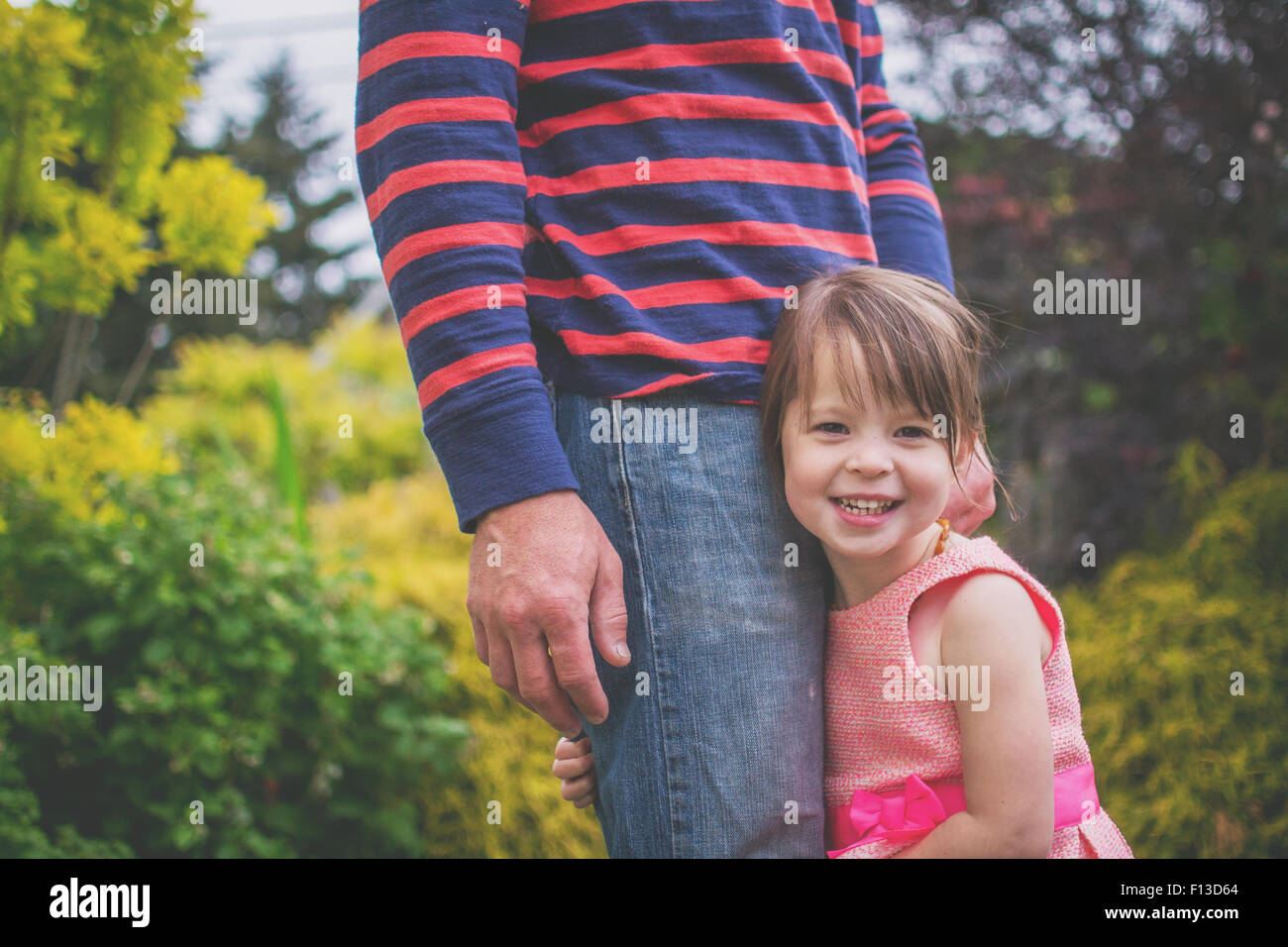 Close-up di un sorridente ragazza abbracciando il padre è la gamba Foto Stock
