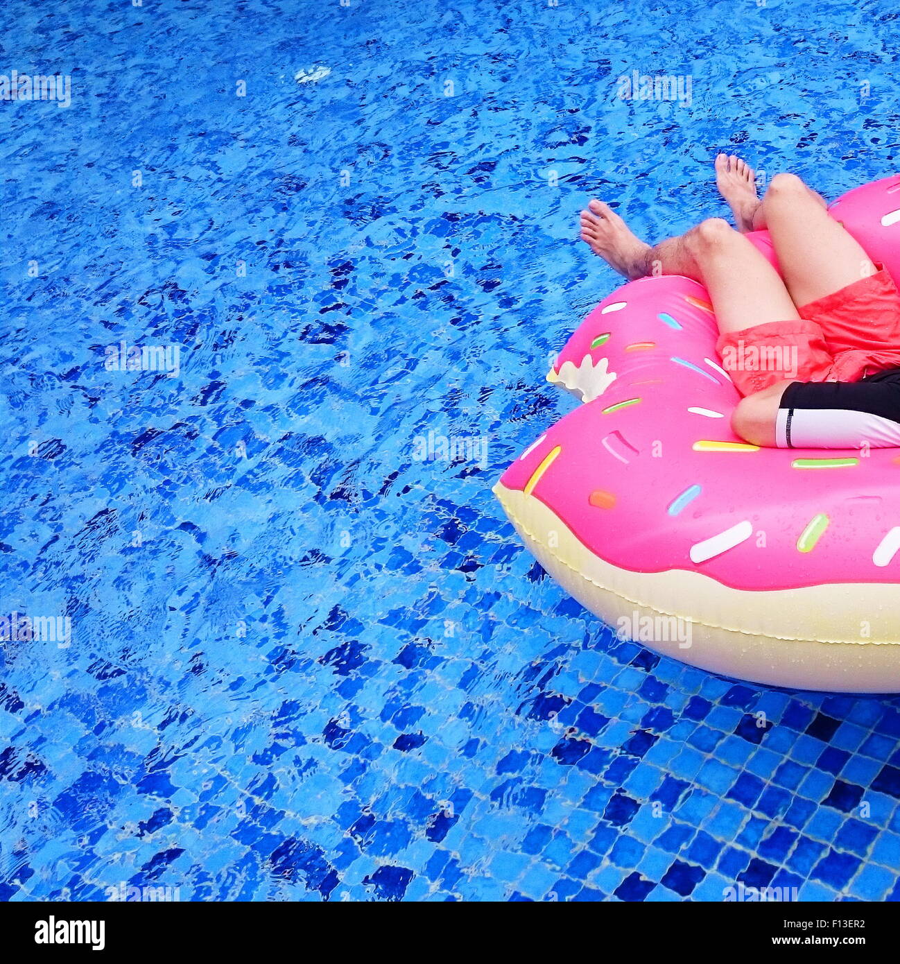 Uomo maturo rilassante sulla ciambella gonfiabile in una piscina Foto Stock
