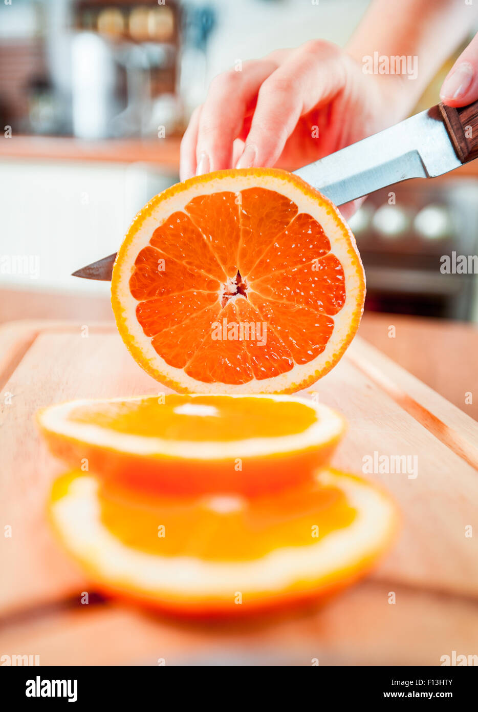 Donna con le mani in mano il taglio di arancia fresca su cucina Foto Stock