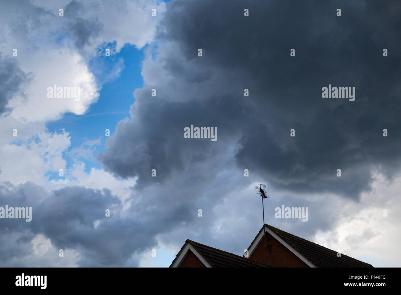 Nuvole temporalesche al di sopra di un tetto con un'antenna televisiva nel Regno Unito Foto Stock