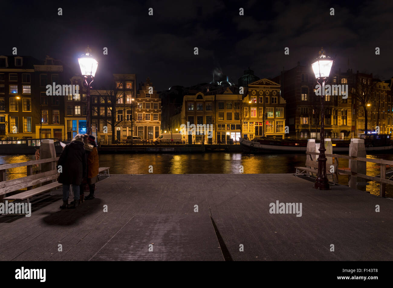 Amsterdam canal di notte con alcuni turisti nella parte anteriore Foto Stock