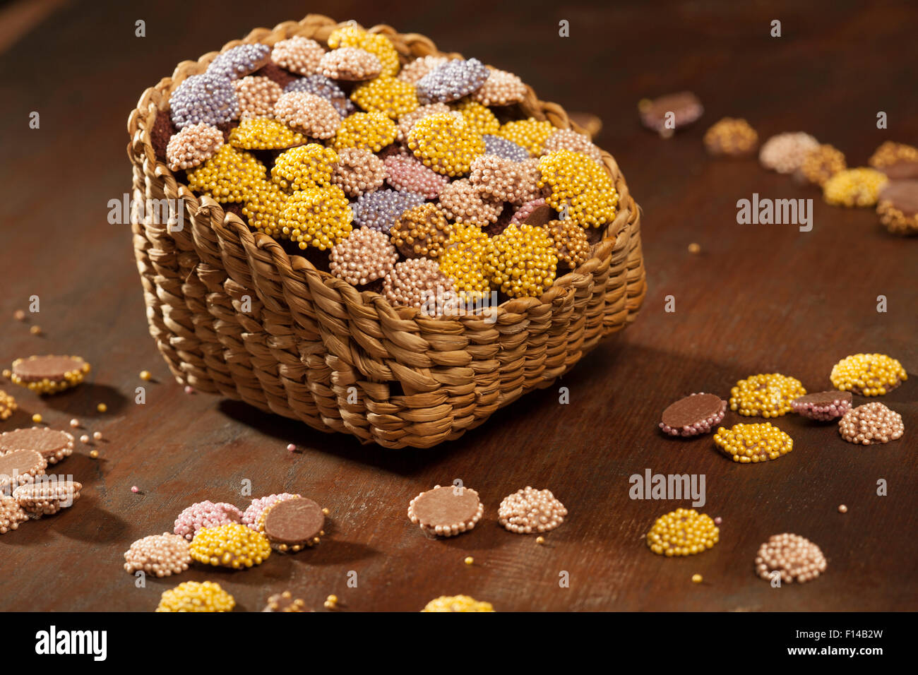 Colorati confetti di cioccolato messi in cesto su uno sfondo di legno Foto Stock