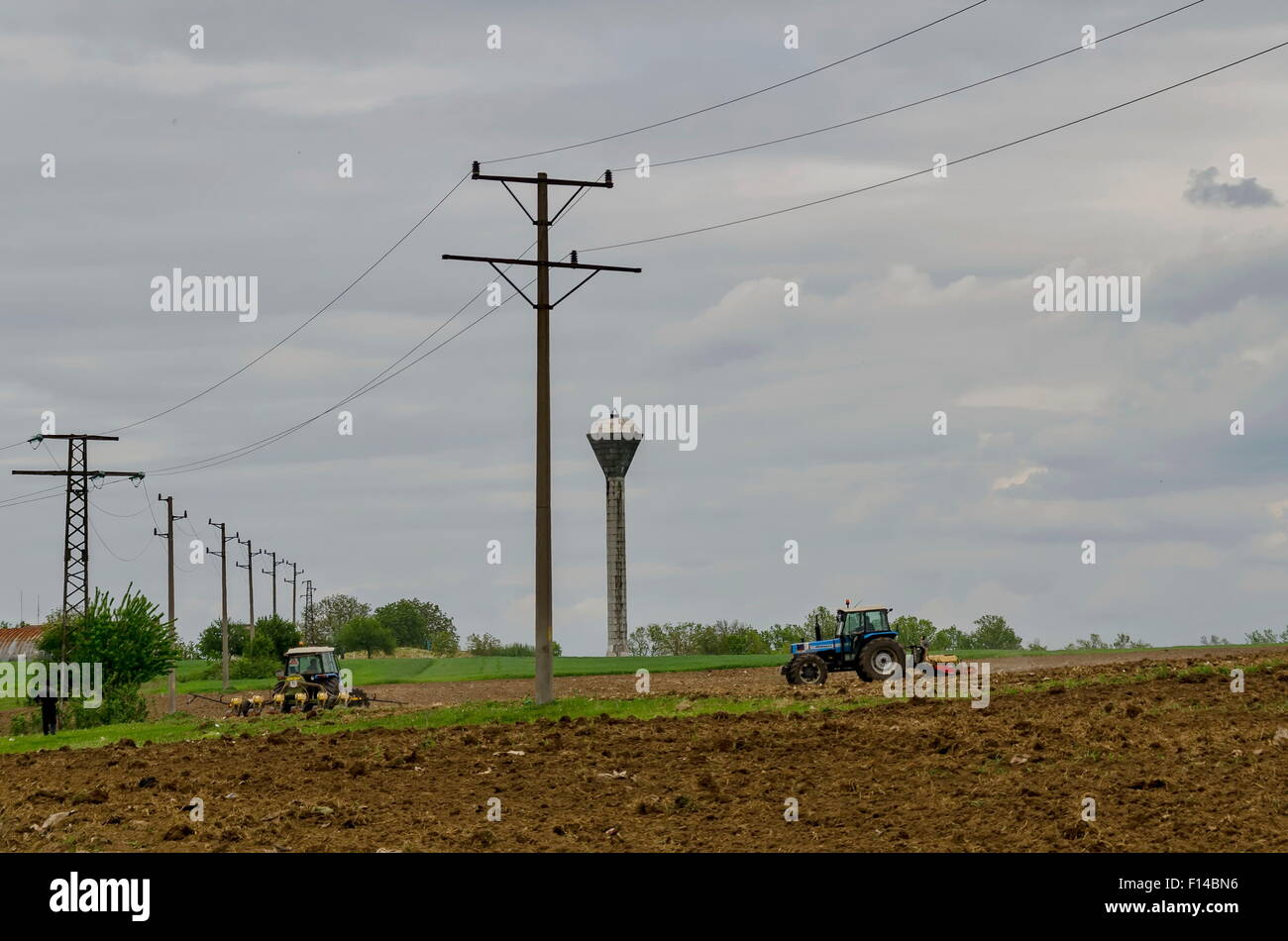 Due trattore con macchina agricola coltivare il campo Foto Stock
