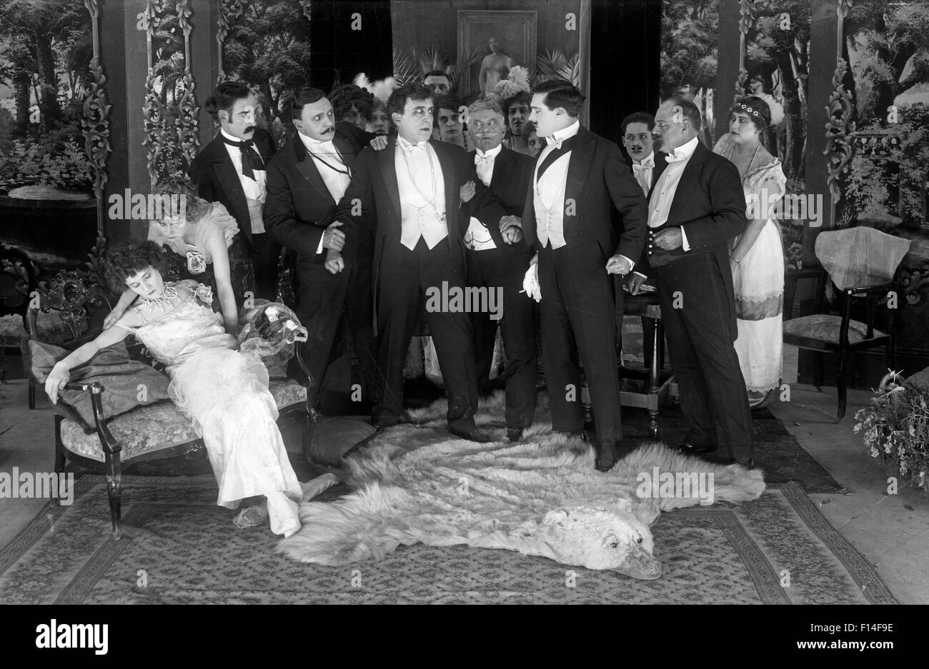 1920s donna svenimento come gruppo di formalmente vestiti gli uomini stanno intorno SILENT MOVIE ANCORA Foto Stock