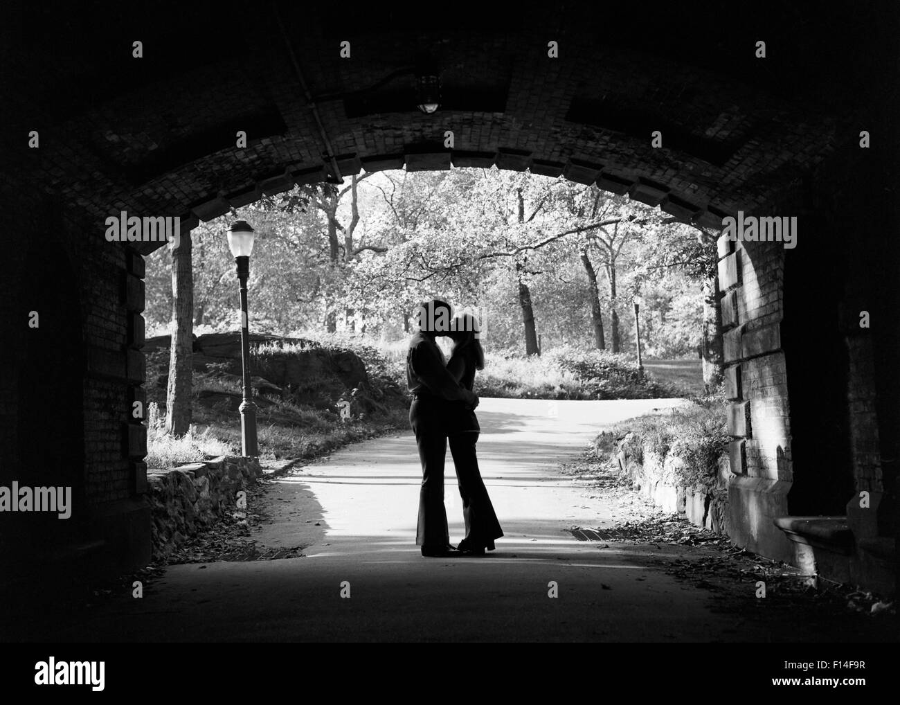 Anni sessanta silhouette di anonimo coppia giovane abbracciando KISSING IN INGRESSO AL PARCO CENTRALE DI TUNNEL DI NEW YORK CITY STATI UNITI D'AMERICA Foto Stock