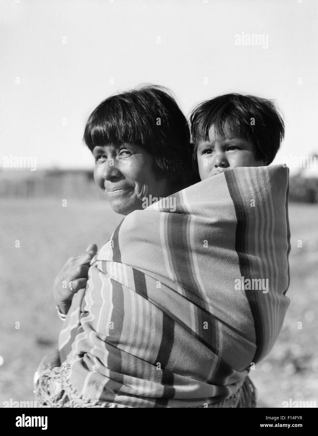 1930s nativa sorridente madre americana guardando la telecamera bambino portando sulla sua schiena COCHITI PUEBLO NEL NUOVO MESSICO USA Foto Stock