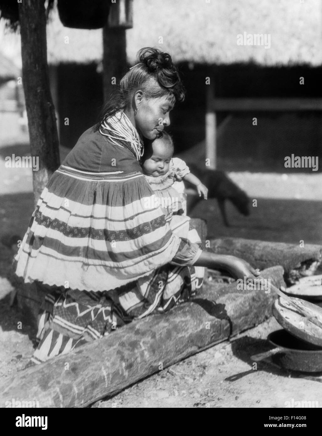 1920s nativi americani donna SEMINOLE tenendo il bambino e la cottura di Florida USA Foto Stock
