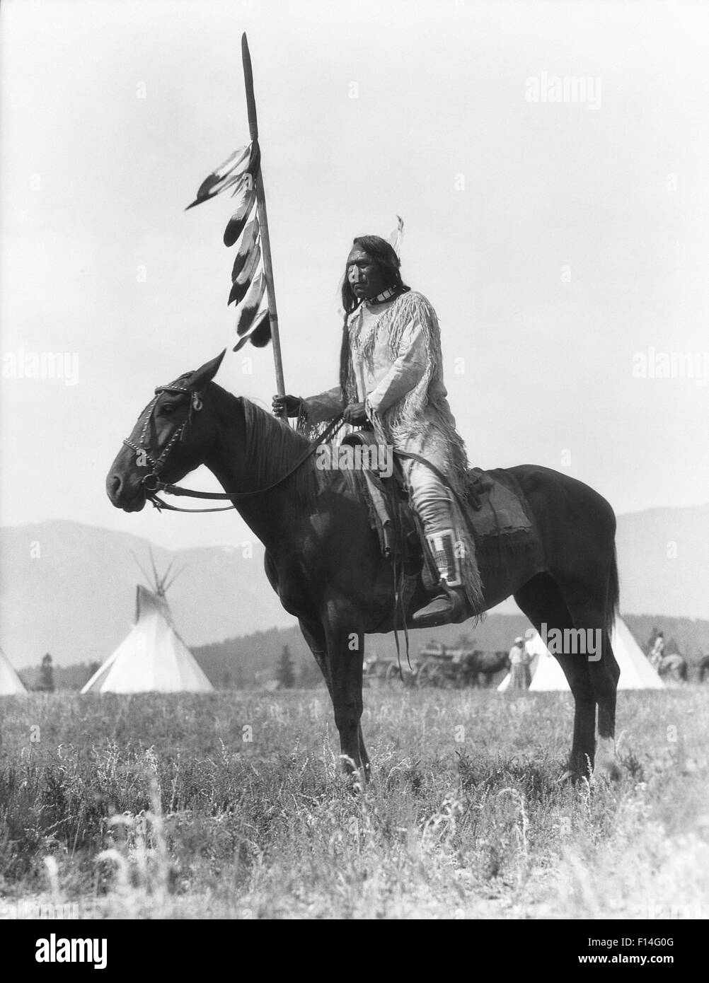 1920s SINGLE NATIVE AMERICAN STONEY indiani Sioux uomo seduto sul cavallo HOLDING EAGLE FEATHERED DECORATE LANCIA ALBERTA CANADA Foto Stock