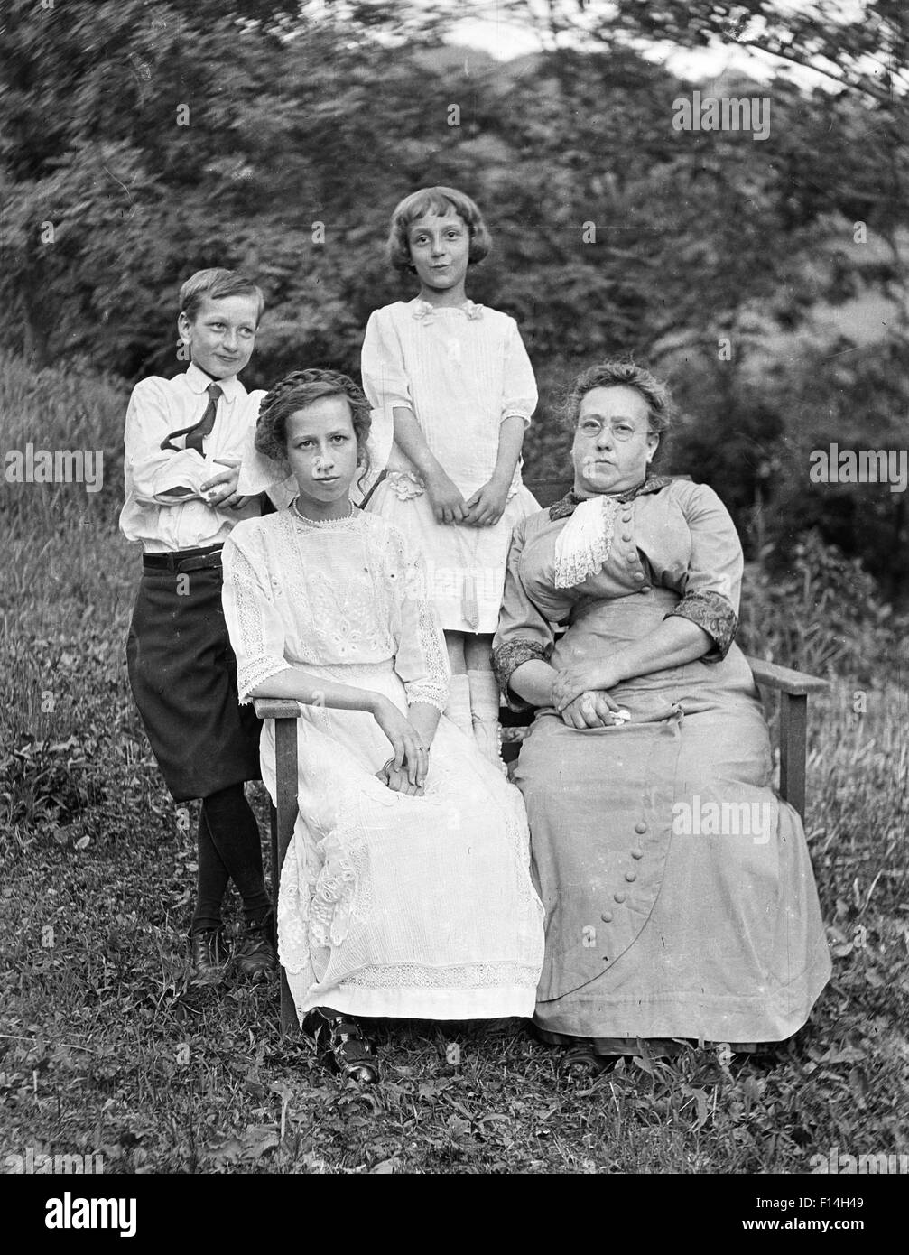 1800s 19esimo secolo e madre di tre bambini seduti e in piedi insieme all'esterno guardando la fotocamera Foto Stock