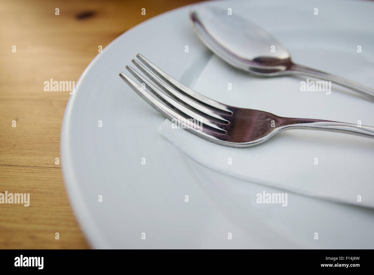 Cucchiaio e forchetta con piastra bianca sulla tavola di legno Foto Stock