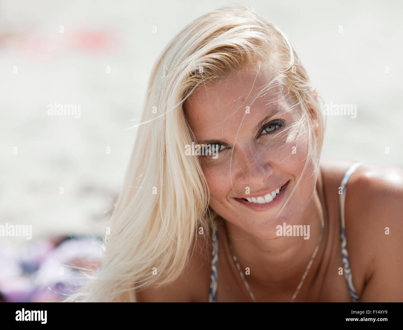 Donna sorridente con capelli biondi posa sulla spiaggia Foto Stock