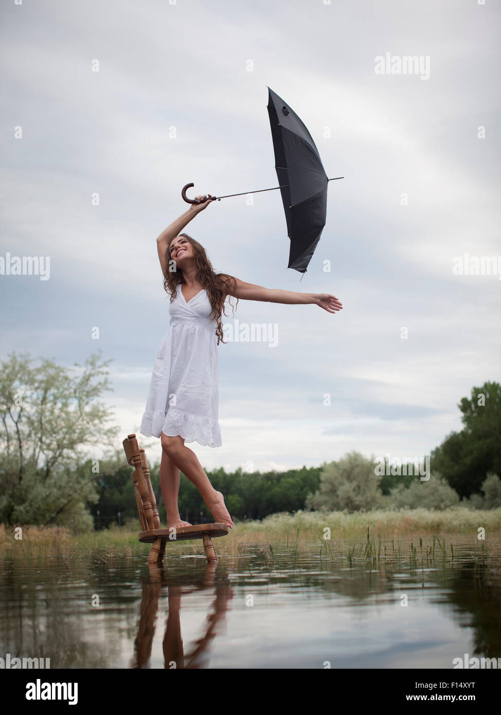 Stati Uniti d'America, Utah, Provo, donna in piedi su una sedia nel lago e ombrello di contenimento Foto Stock