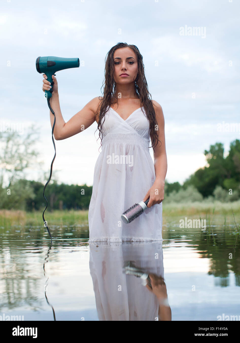 Stati Uniti d'America, Utah, Provo, donna guadare in lago holding asciugacapelli e spazzola per capelli Foto Stock