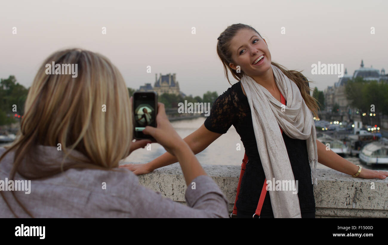 Donna prendendo fotografia di amico sul ponte, Parigi, Francia Foto Stock