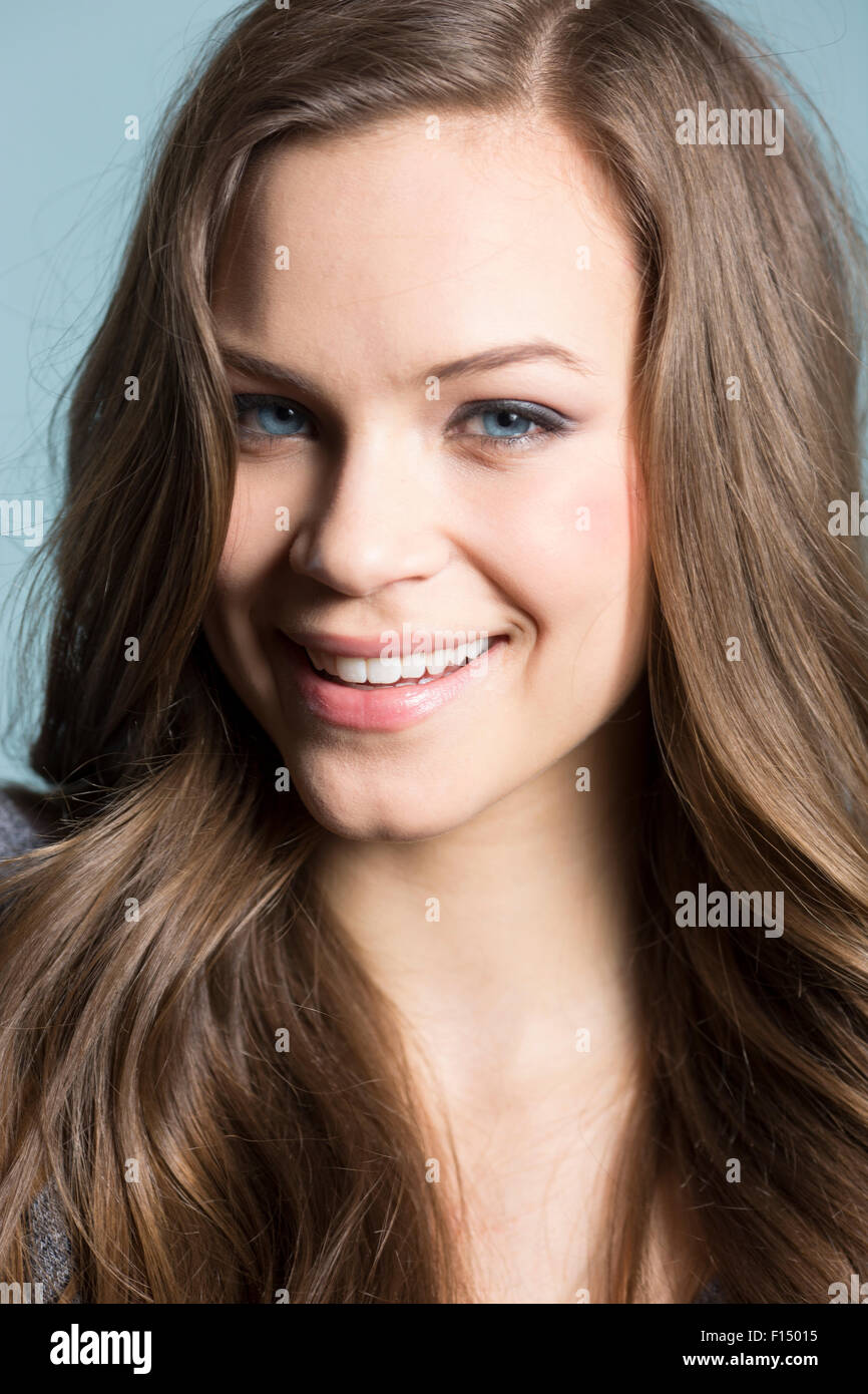 Close up di donna sorridente con lunghi capelli castani e gli occhi blu Foto Stock