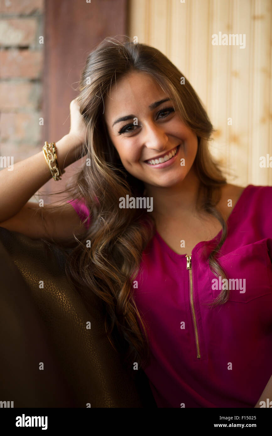 Vita di donna sorridente con capelli lunghi marrone seduto sul divano Foto Stock