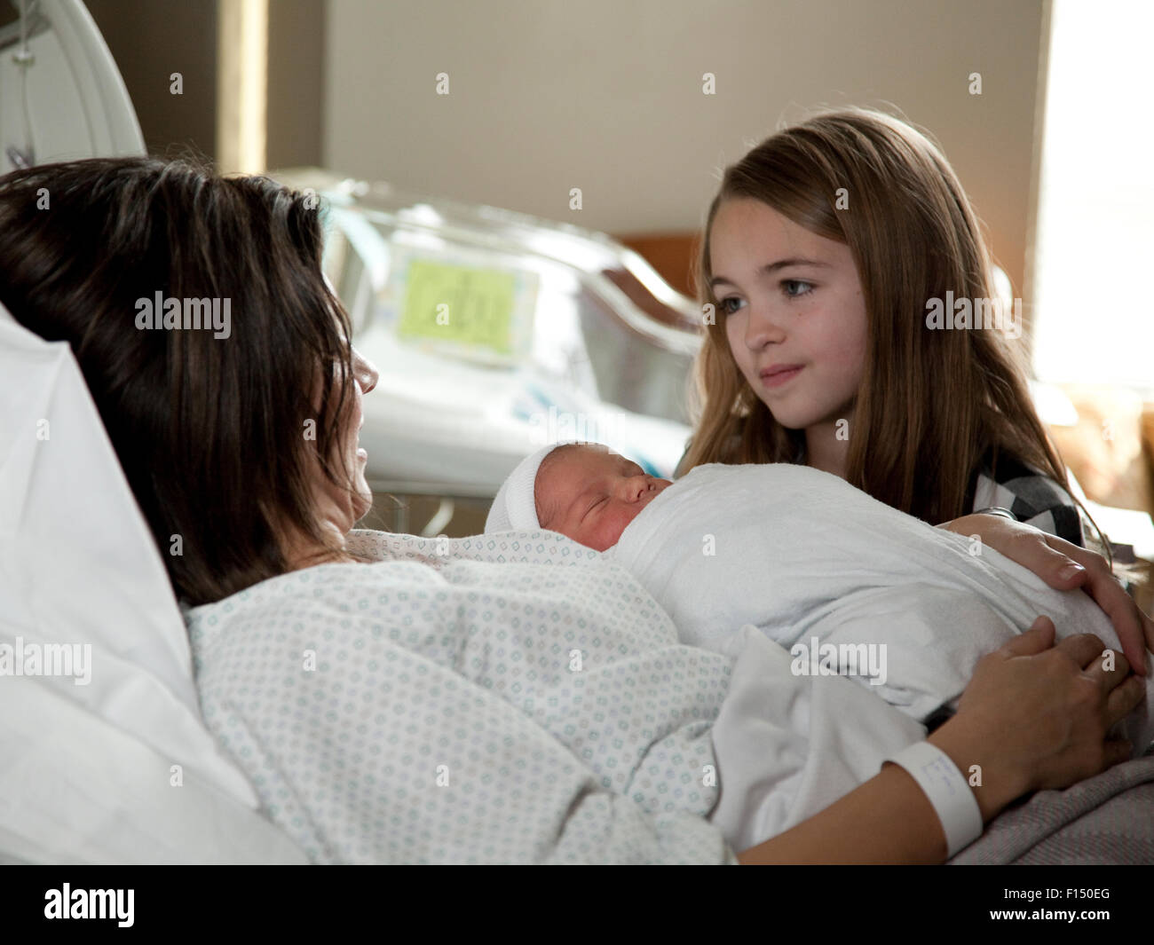 Stati Uniti d'America, Utah, Payson, ragazza (8-9) con la madre e il bambino (0-1 mesi) a letto Foto Stock