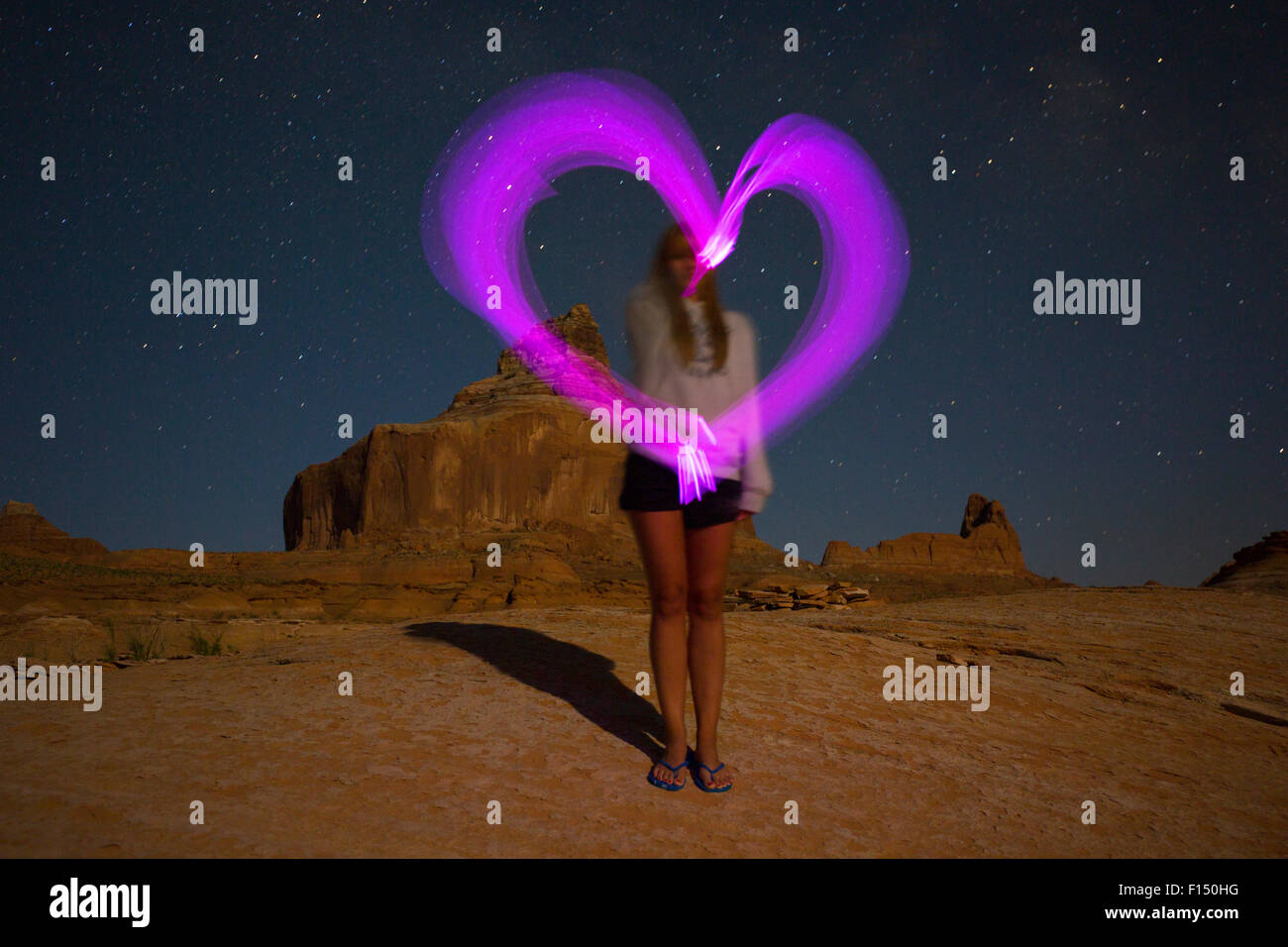 Time Lapse vista della donna cuore di disegno sul deserto remoto collina sotto il cielo stellato Foto Stock
