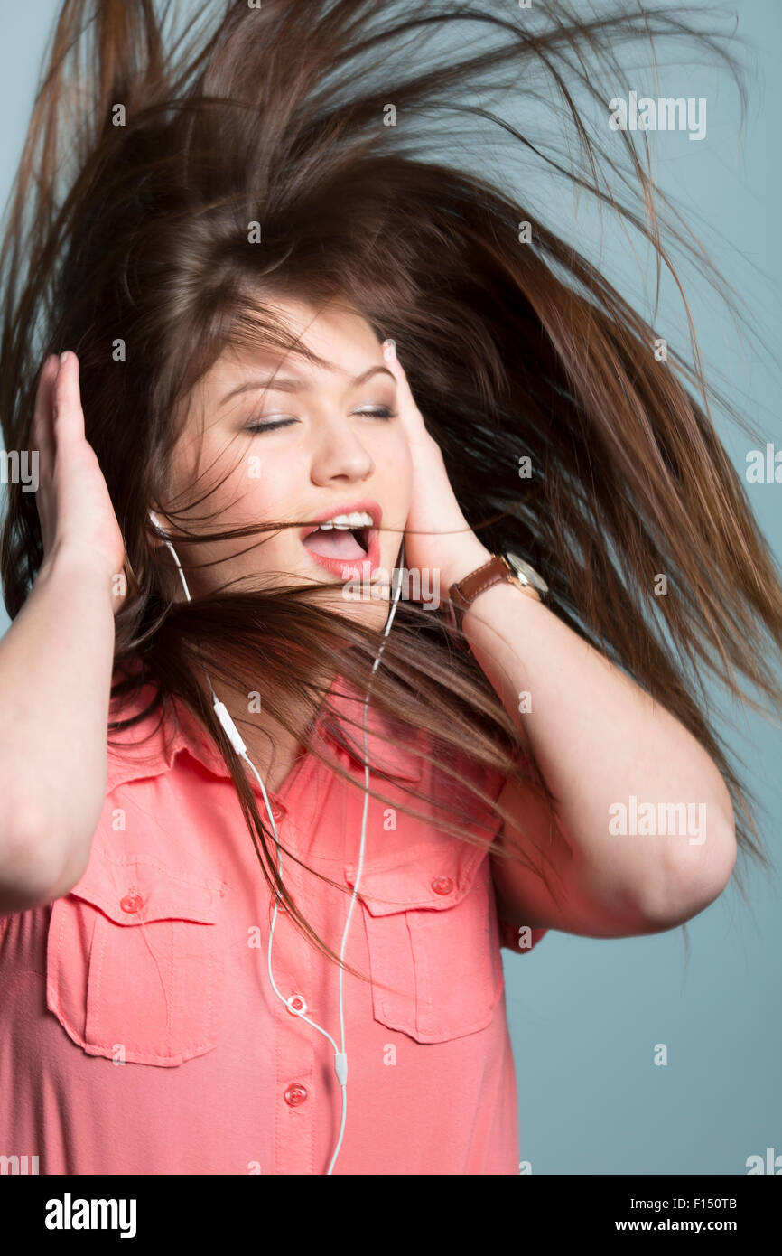 Giocoso donna con capelli lunghi marrone ballare con la musica in cuffia Foto Stock