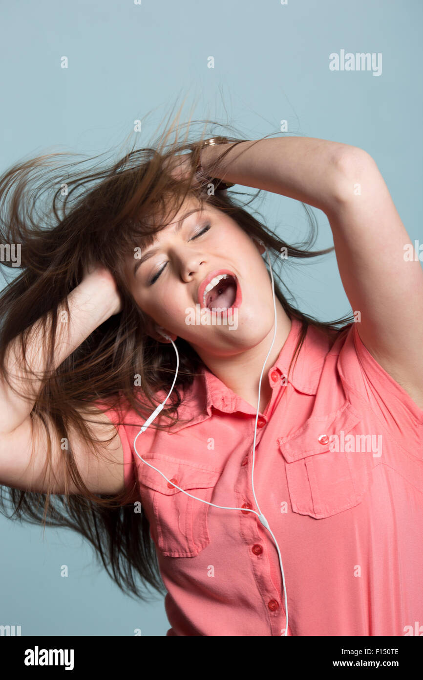 Giocoso donna con capelli lunghi marrone ballare con la musica in cuffia Foto Stock