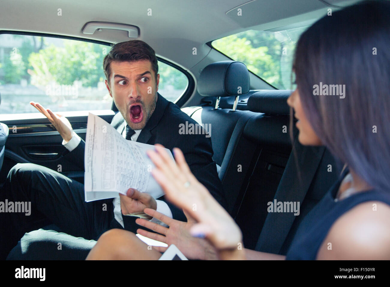 Angry Man holding documenti gridando su una donna in auto Foto Stock
