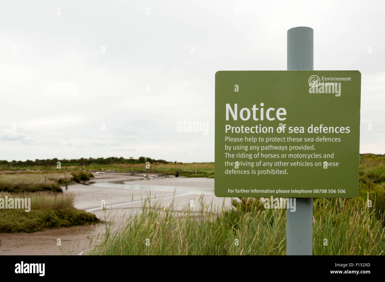 Un'agenzia per l'ambiente segno sulla protezione delle difese del mare nella parte anteriore del Norfolk paludi costiere. Foto Stock