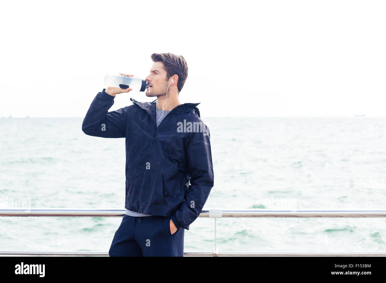 Ritratto di un uomo di sport nelle cuffie acqua potabile all'aperto Foto Stock