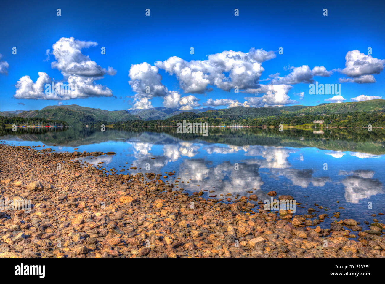 Il Lake District inglese England Regno Unito a Ullswater con le montagne e il cielo blu sulla bellissima giornata estiva con riflessioni in HDR Foto Stock