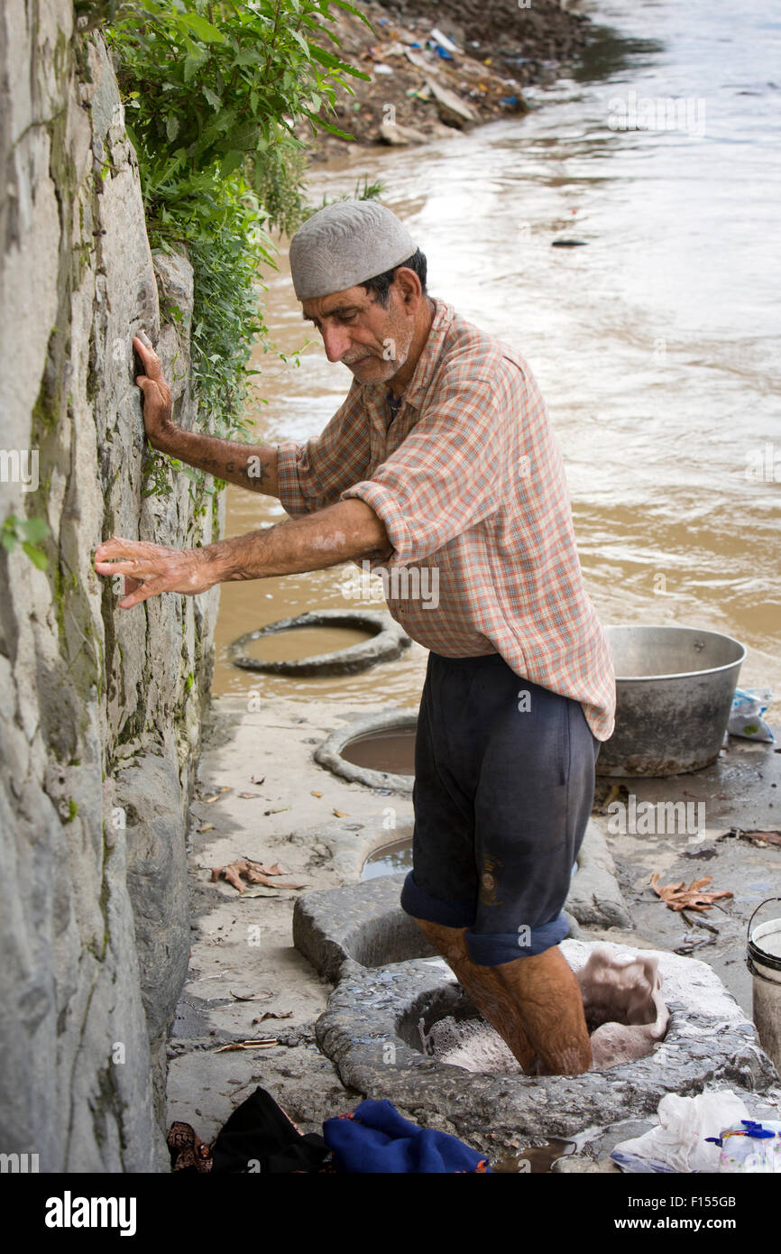 India, Jammu e Kashmir Srinagar, città vecchia, fiume Jhelum riverside ghat, uomo pashminas lavaggio con piedini Foto Stock